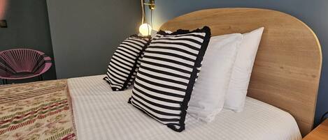 A bed with striped pillows, a wooden headboard, and a patterned blanket.