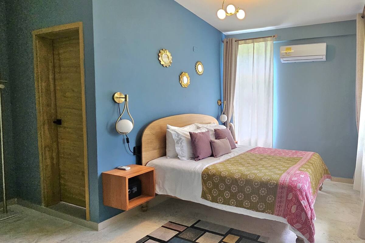 A bedroom with a bed, nightstand, wall decorations, and an air conditioning unit.