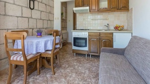 A compact kitchen with wooden cabinets, a built-in oven, and a dining area with a table and chairs.