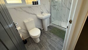 A bathroom with a toilet, sink, and shower. - Hideaway 4-Bed House in Bridgend" (Bridgend County Borough)