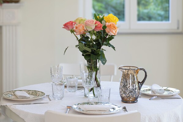 A dining table set with plates, glasses, a pitcher, and a vase with flowers.