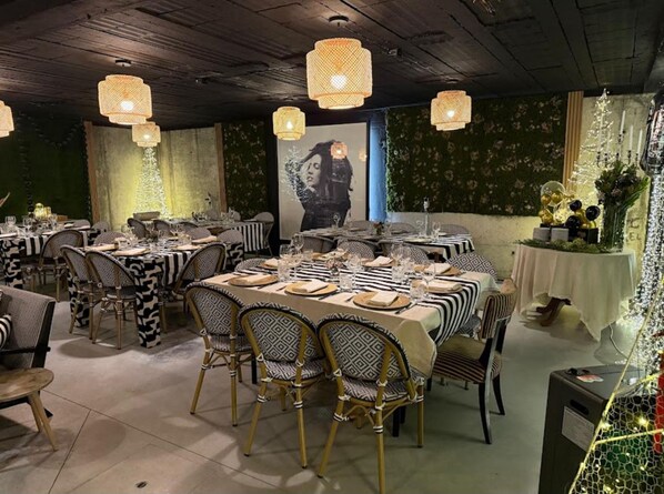 A restaurant with tables set for dining, featuring patterned tablecloths and wicker chairs.