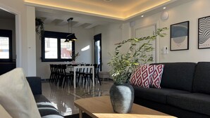 Un salon moderne avec un canapé foncé, une table basse en bois et un coin repas à l’arrière-plan.