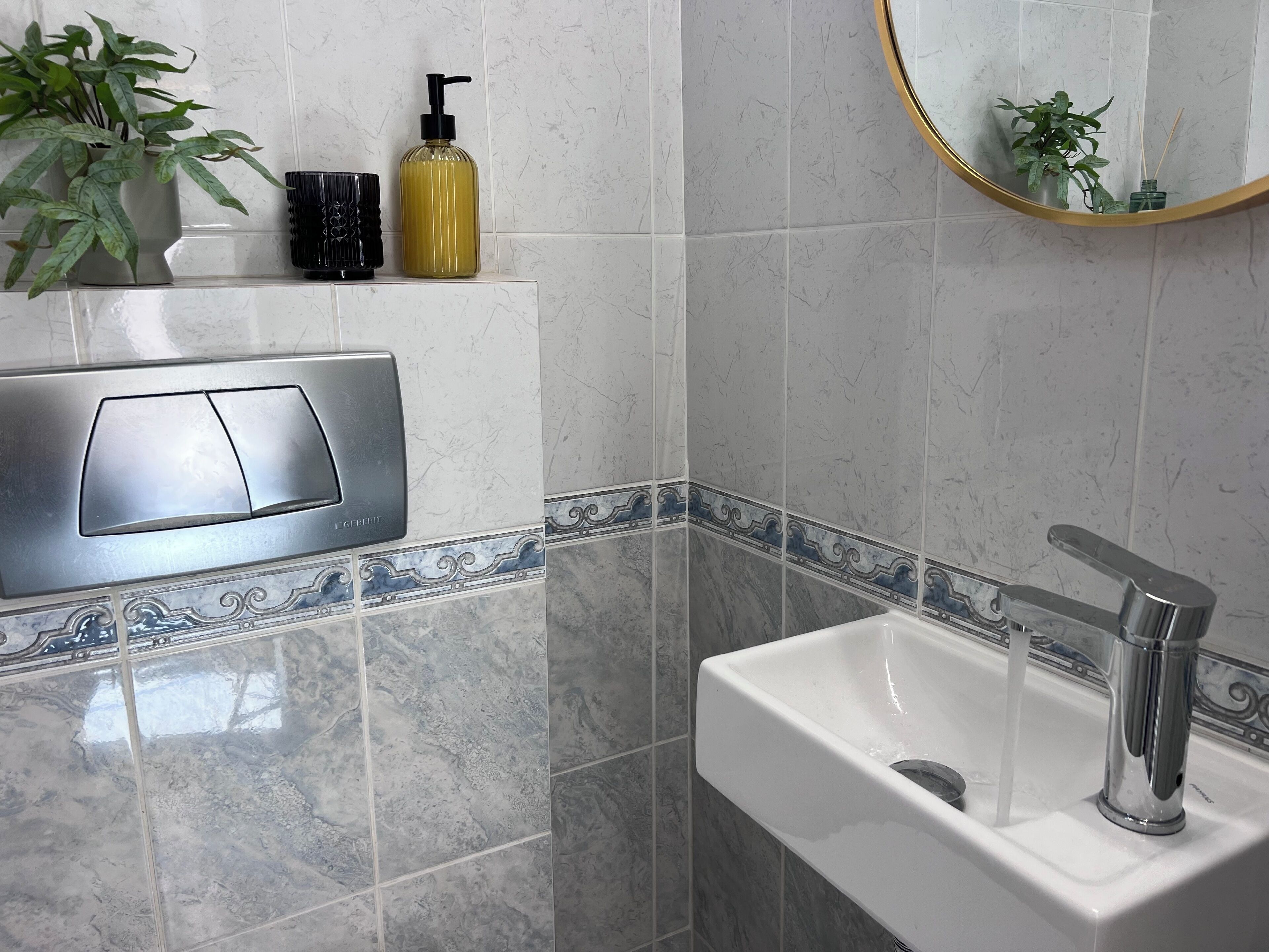 A bathroom with a white sink, chrome faucet, and a marble backsplash. There is a hand dryer and a bottle of hand soap on the wall.