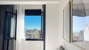 Une chambre d’hôtel avec vue sur le paysage urbain, visible par une fenêtre ouverte.