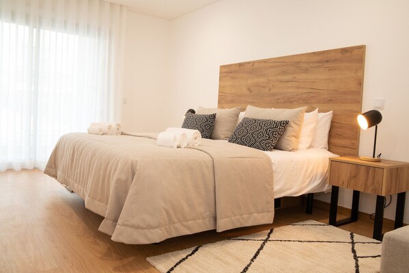 A bedroom with a bed, bedside tables, a lamp, and a window with curtains.