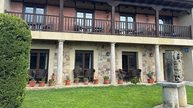 A two-story building with a balcony, stone columns, and potted plants. - Hospedería Rural Santa Cruz (Socobio)