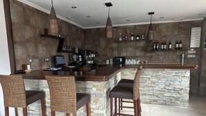 A bar area with a stone countertop, wicker chairs, and hanging light fixtures. - Hospedería Rural Santa Cruz (Socobio)