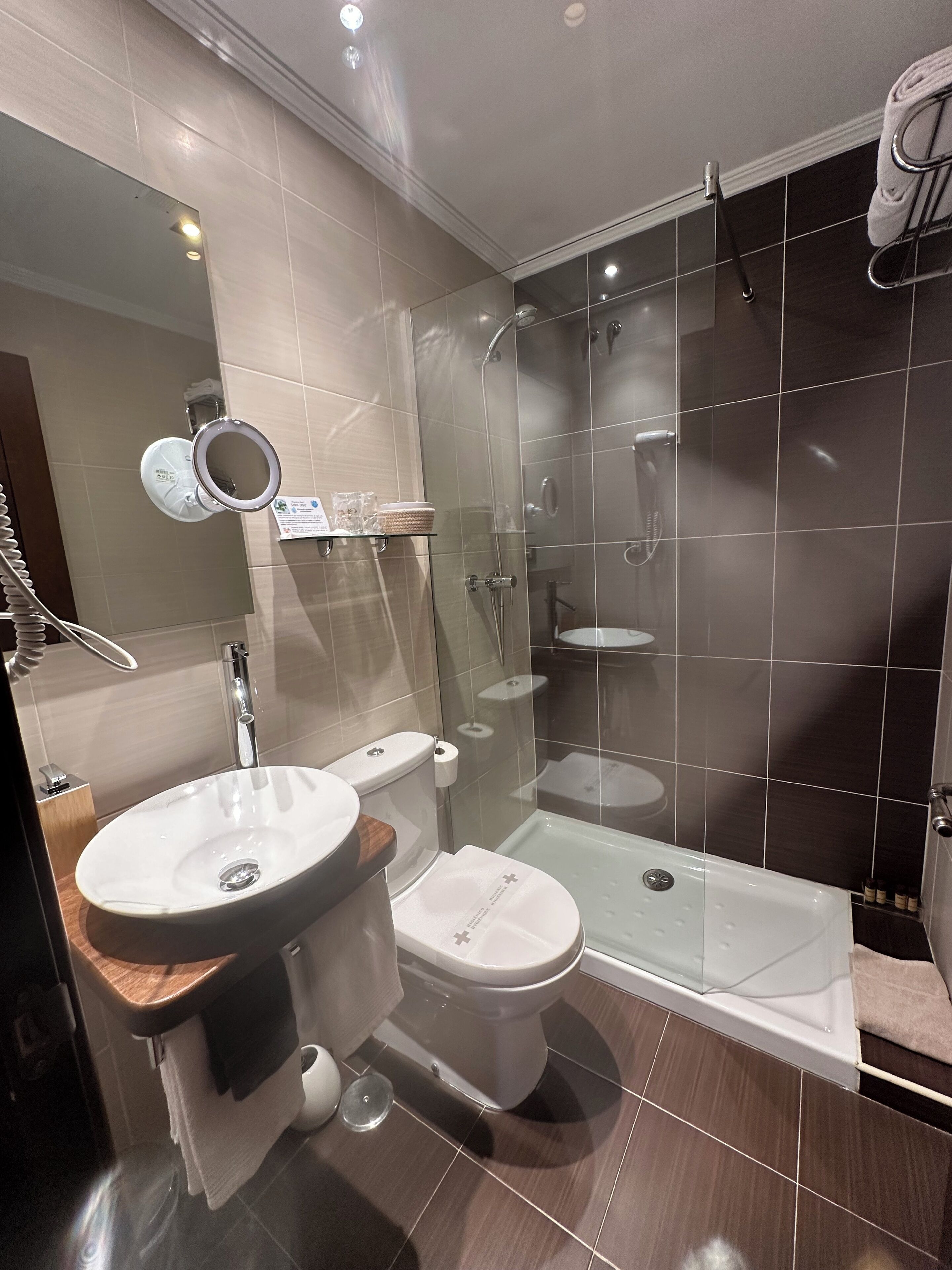 A modern bathroom with a glass-enclosed shower, a white sink, and a toilet.