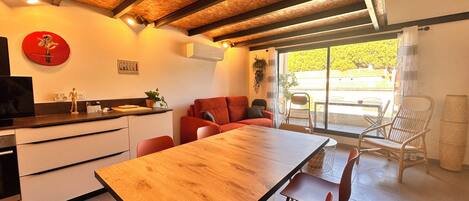Una cocina moderna con una mesa de madera y sillas rojas, un sofá rojo y un ventanal con vistas a zonas verdes.