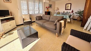 A living room with a sofa, a glass coffee table, a television, and a cabinet.