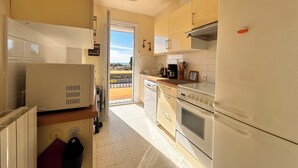 A kitchen with a refrigerator, stove, and oven. There is a window with a view of the outdoors.