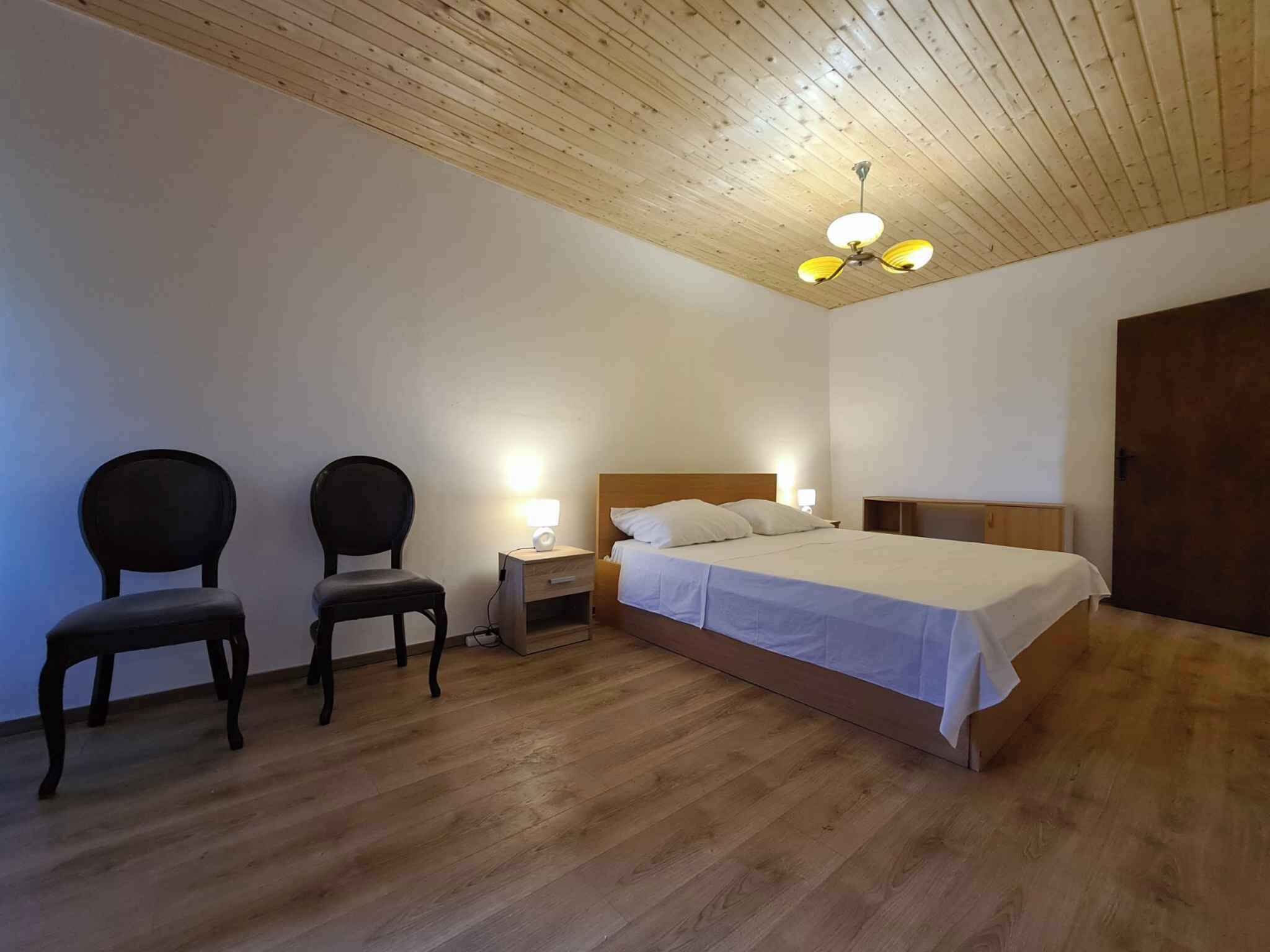 Ein Schlafzimmer mit Holzboden, einem Bett mit weißer Bettwäsche, zwei Stühlen und Nachttischlampen.