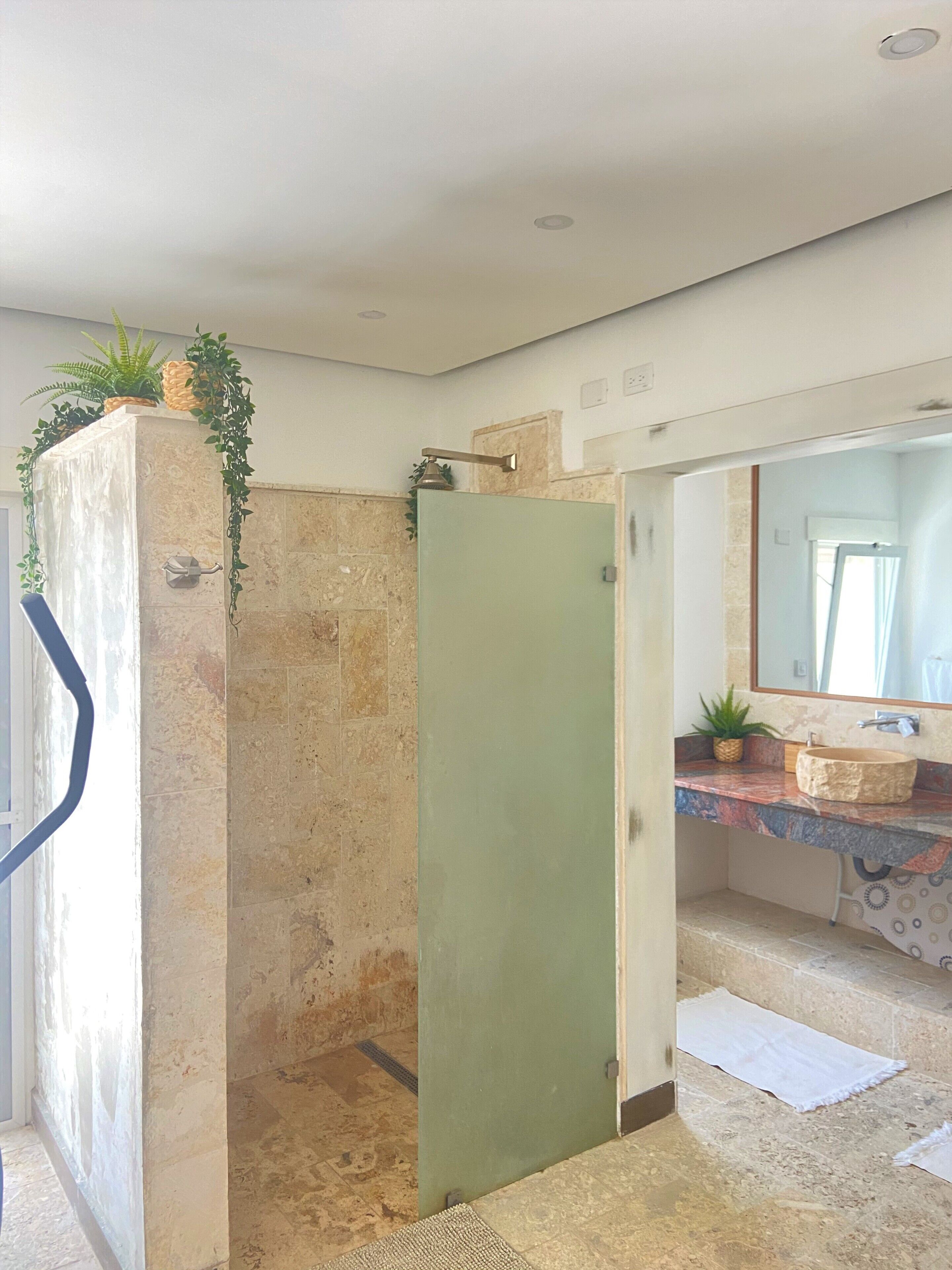 Ein Badezimmer mit Dusche, einem Waschbecken mit Marmorplatte und einem Spiegel darüber.
