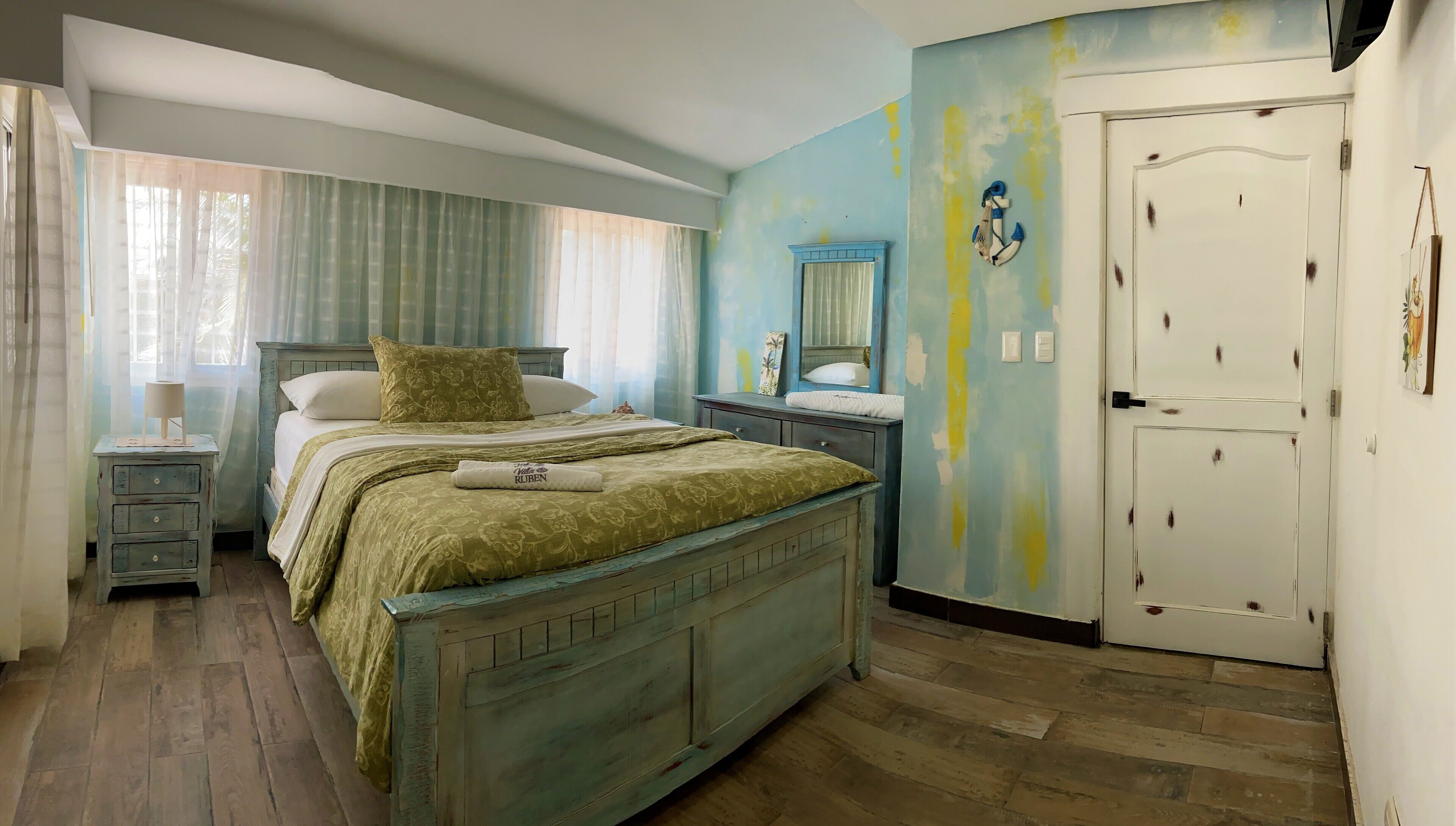 A bedroom with a bed, bedside tables, a dresser, a mirror, and a door.