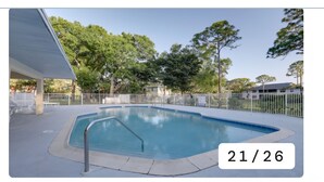 A swimming pool with a metal handrail, surrounded by a white fence and trees. - Charming 2-bedroom condo with AC, WiFi in quaint Stuart (Stuart)
