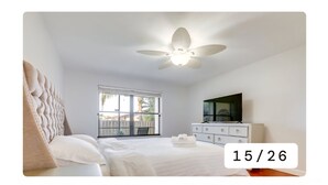A bedroom with a bed, a ceiling fan, a window, a dresser, and a TV. - Charming 2-bedroom condo with AC, WiFi in quaint Stuart (Stuart)