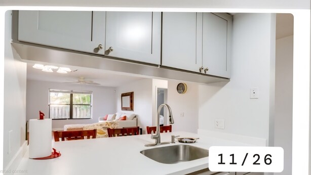 A modern kitchen with white cabinets, a stainless steel sink, and a dining area with a table and chairs. - Charming 2-bedroom condo with AC, WiFi in quaint Stuart (Stuart)
