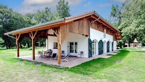 Una casa de madera con un porche cubierto, un comedor y un ventanal grande.