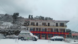 A two-story building with a red and yellow facade, a balcony on the upper floor, and a sign indicating it is a hotel and restaurant. - Hotel Himalaya View (Dehradun)