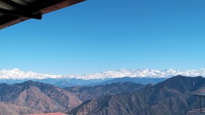 A mountainous landscape with snow-capped peaks under a clear blue sky. - Hotel Himalaya View (Dehradun)
