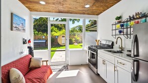 A modern kitchen with a red sofa, a gas stove, and a stainless steel refrigerator. - Orchard Oasis Retreat (West Palm Beach)