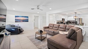A spacious living area with a brown leather sofa, a massage chair, and a round coffee table. - Orchard Oasis Retreat (West Palm Beach)