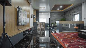Un interior moderno con un revestimiento de madera, un cuadro grande, suelo de mármol negro, alfombra roja estampada y un acuario.