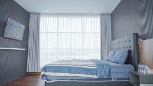 Un dormitorio moderno con una cama grande, un cabecero, una mesita de noche y una ventana con cortinas traslúcidas.