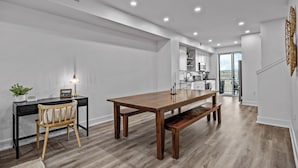 A spacious kitchen with modern appliances, a dining area with a wooden table and bench, and a view to the outdoors.
