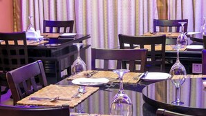 A dining area with round tables, chairs, and wine glasses. - Guaranty Inn Hotel and Suites  (Abuja)