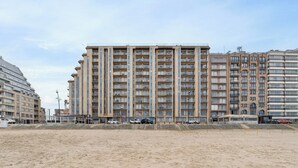 A high-rise residential building with multiple balconies, located adjacent to a sandy beachfront. - Studio in Blankenberge Near the Beach (Blankenberge)