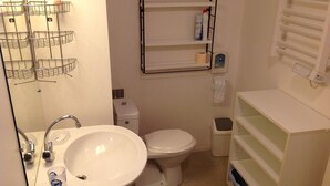 Une petite salle de bain comprenant un lavabo, des toilettes et des étagères de rangement.