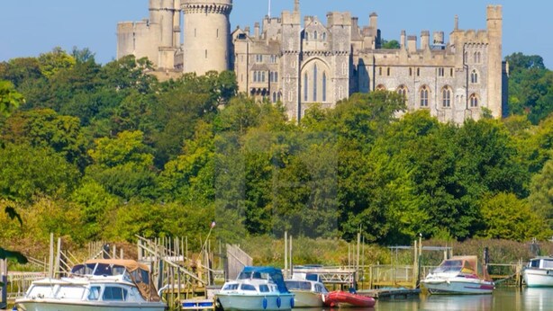 A castle on a hill with boats docked in a calm water body in the foreground. - Arundel Cottage Retreat (Arundel)