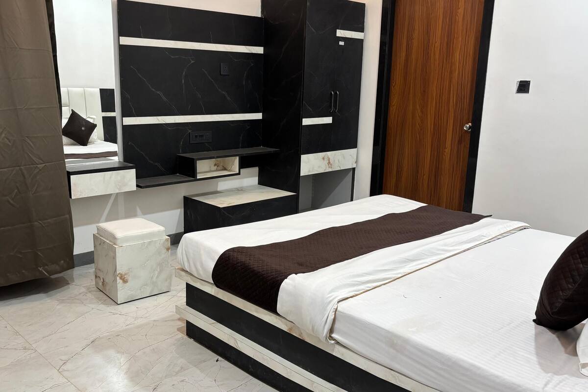 A bedroom with a bed, a nightstand, a dresser, and a mirror.