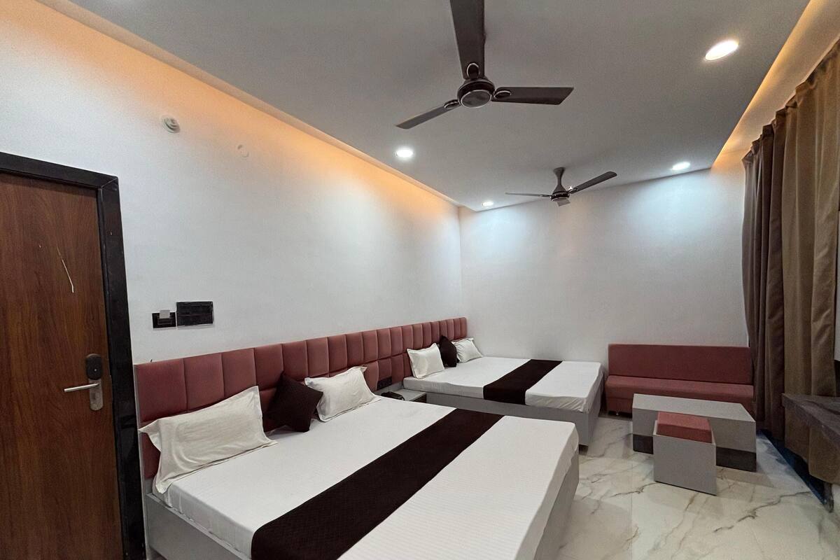A hotel room with two beds, a seating area, and ceiling fans.