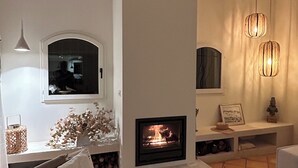 A modern living room with a fireplace, white walls, and a tiled floor. - Magnificent villa with panoramic view of the Mediterranean Sea (Le Lavandou)