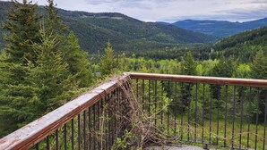 Barandilla de madera con vistas a un paisaje montañoso y boscoso.