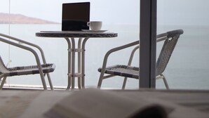 En balkon med en bærbar computer, en kop og to fletstole.