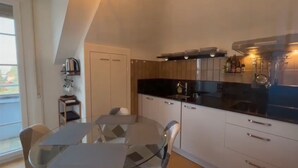Een moderne keuken met een zwart aanrecht, witte kasten en een glazen eettafel.