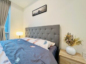 Cozy retreat with a neatly made bed, framed artwork, and a stylish nightstand.