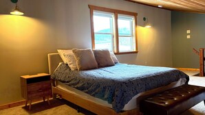 Ein Schlafzimmer mit einem Holzbett, einer Bank, einem Nachttisch und zwei Wandlampen.