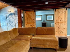 Ein gemütliches Wohnzimmer mit einem großen Ecksofa, Holzwänden und einem Kamin.