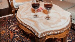 A cozy interior with a round table, two wine glasses, a sofa, and ornate chairs in a cave-like setting. - 7 Oda Kapadokya Cave House (Urgup)