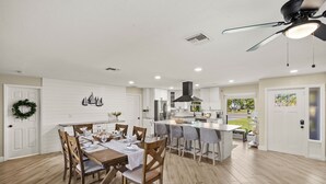 A spacious kitchen with white cabinetry, a central island, and a dining area with wooden chairs and a table set for four.