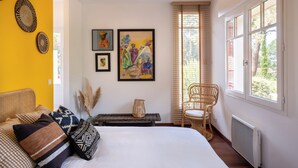 Un dormitorio con una cama, una silla y obras de arte en la pared.