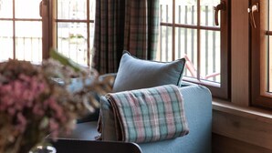 A cozy room with a blue sofa, a plaid blanket, and a window with curtains. - Escape to Nature in Vencimont (Gedinne)