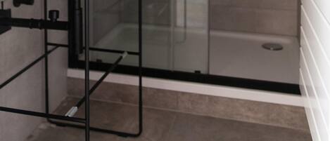 A modern bathroom with a glass shower enclosure, a white sink with a black faucet, and a towel on the sink.