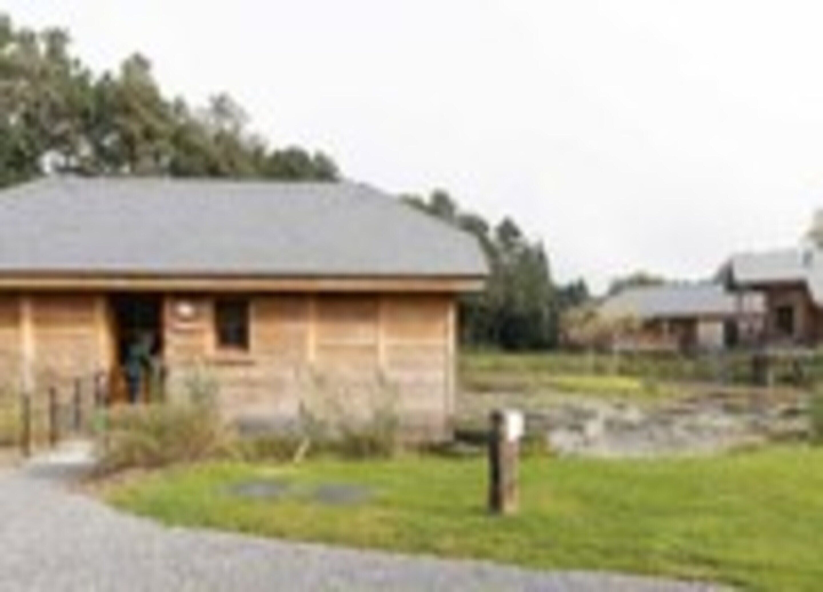 A wooden building with a sloped roof, a door, and a small window.