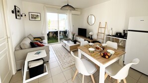 Ein modernes, helles Wohnzimmer mit einer Couch, einem Couchtisch und einem Essbereich.